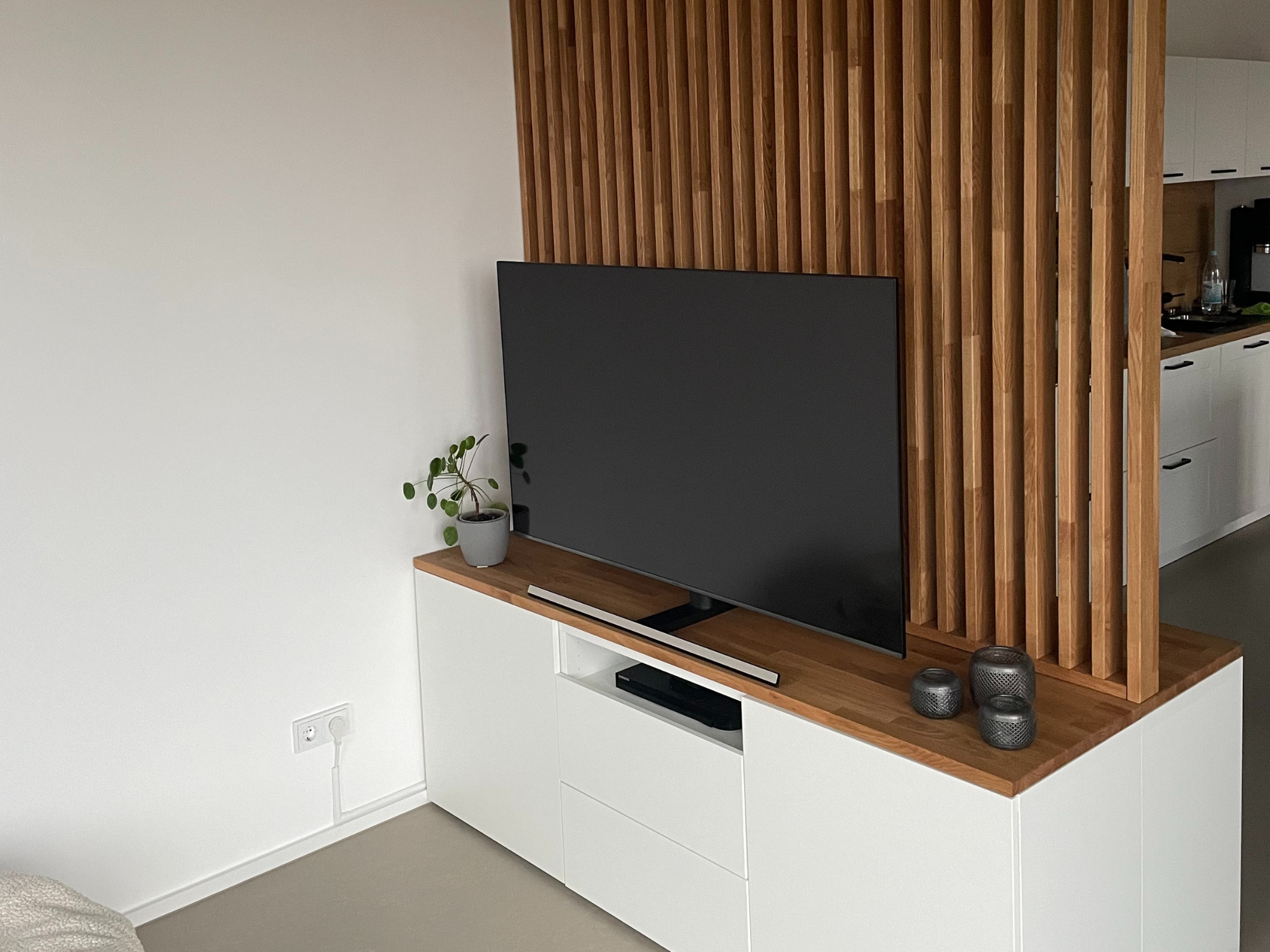 Ikea Besta 3 breiter Korpus mit Massivholzdeckplatte aus Eiche Natur geölt mit Raumtrenner Hack. Wohnbild mit Dekoration.