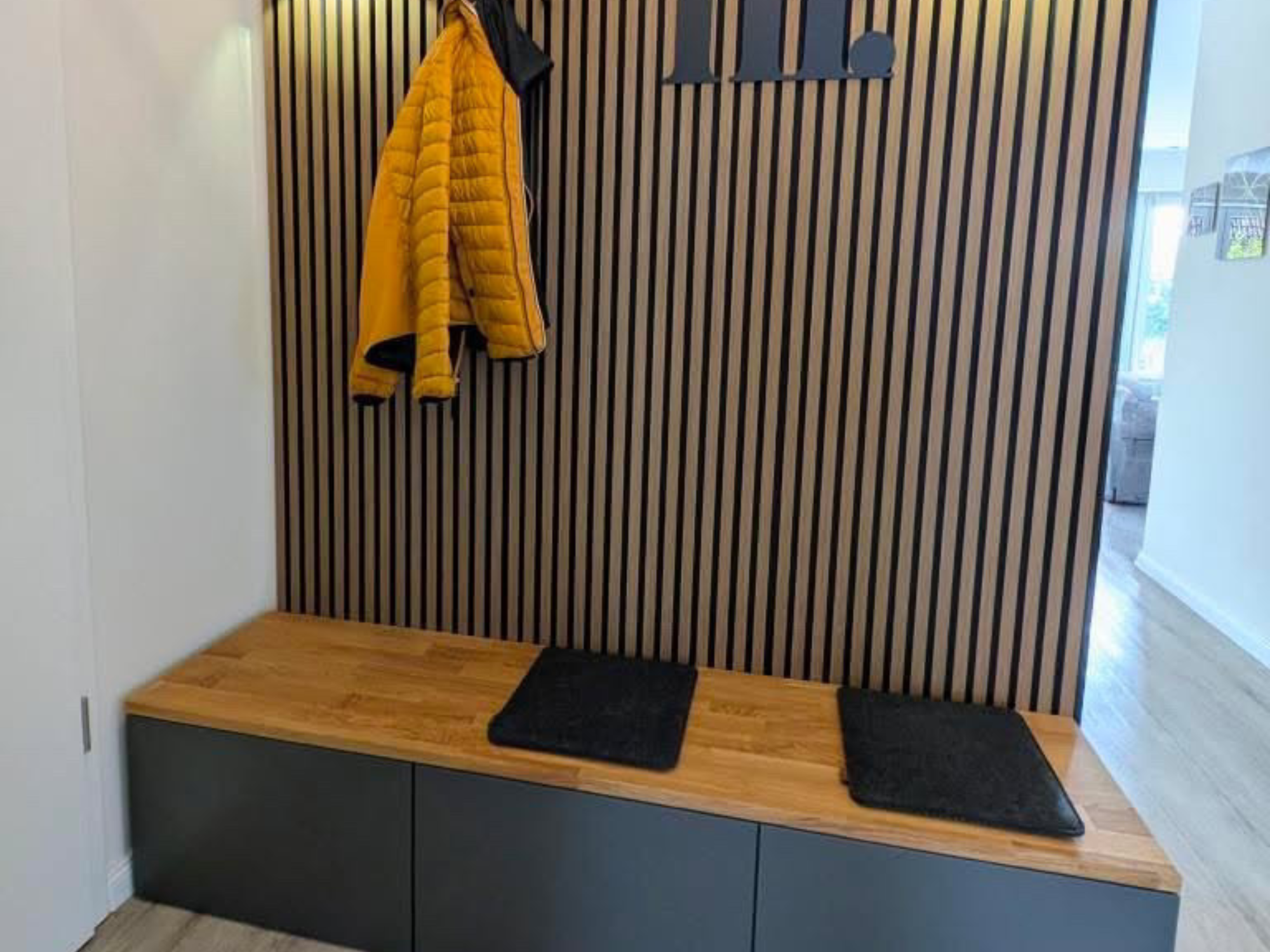 IKEA Besta 3 in Schwarz mit Massivholzdeckplatte aus Eiche in Natur geölt kombiniert mit Akustikpaneele und schwarzen Details für einen modernen Look. Dekoriert und dargestellt als Wohnbeispiel für einen modernen Eingangsbereich.